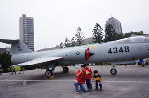 A mother with her two children pose in front of a decommissioned F-104 fighter jet.